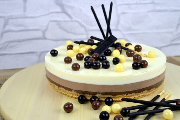 Tarta de tres chocolates con capas de chocolate negro, con leche y blanco sobre base de galleta, decorada con perlas y palitos de chocolate